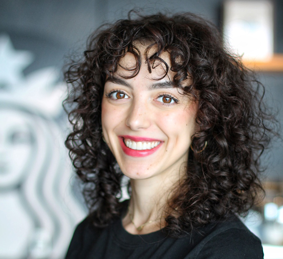 Una mujer sentada en un taburete junto a un podio